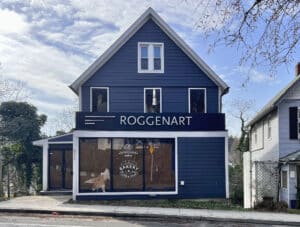 Two and one-half story frame building with blue siding and white trim featuring a storefront window.