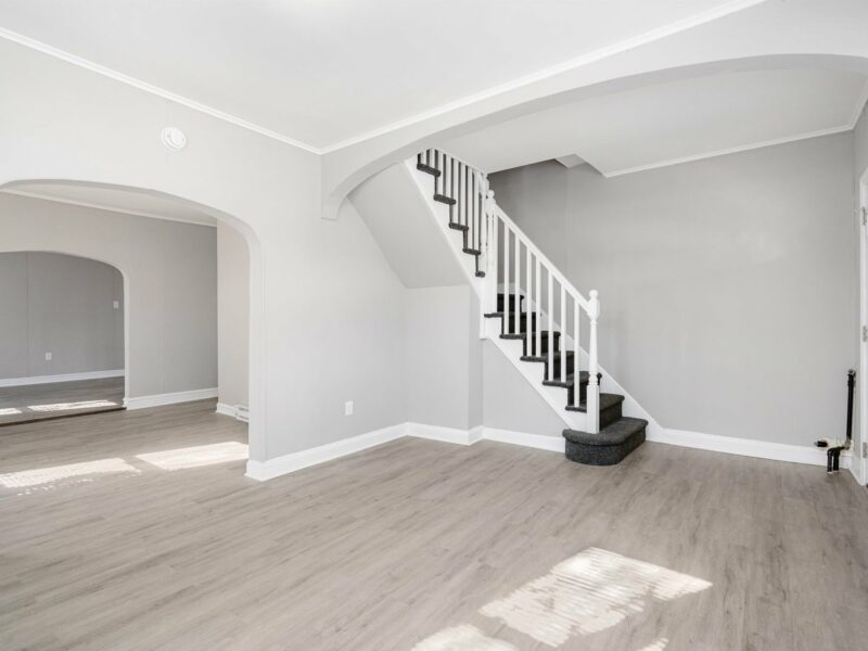 Living room at 5248 Cordelia Avenue with luxury vinyl plank flooring, arched entryways, and staircase to upper level.