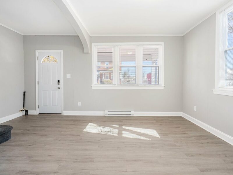 Living room at 5248 Cordelia Avenue with front entry door, large windows, and updated vinyl flooring.