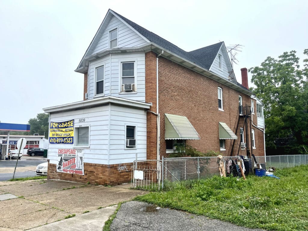 Front and side view of 5839 Belair Road, a freestanding mixed-use commercial building with signage and chain-link fence.
