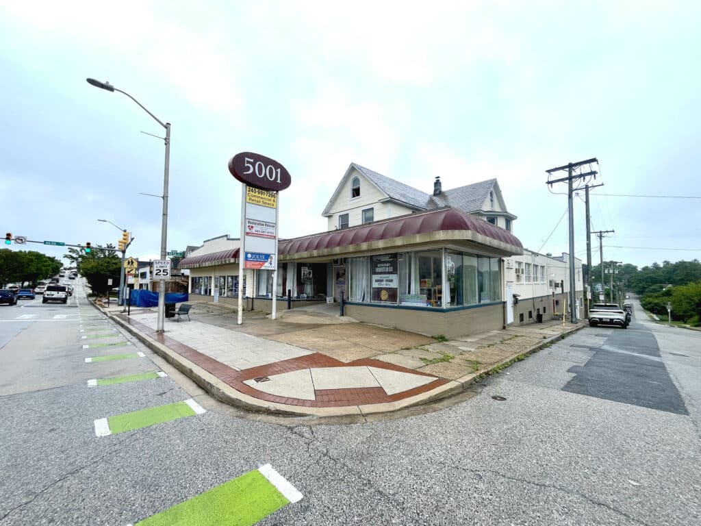 Corner view of commercial building at 5001-5003 Harford Road with red awnings and pole signage.