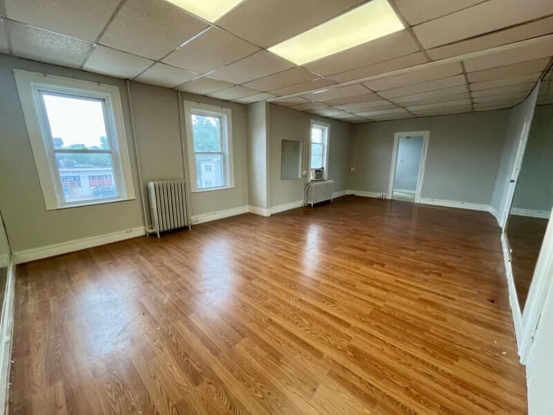 Spacious second-floor middle unit with wood-look flooring, drop ceiling, and multiple windows at 5839 Belair Road.
