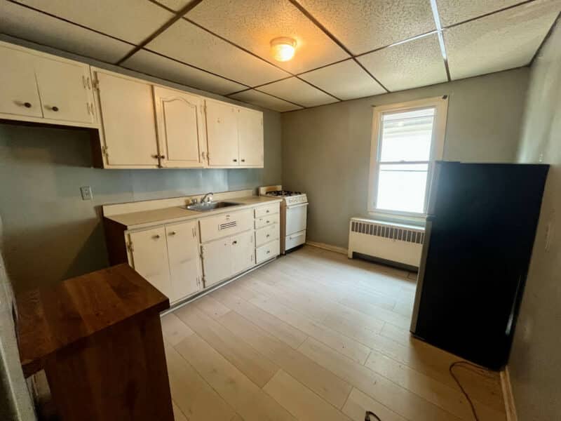 Kitchen of Apartment 1 at 4831 Belair Road with upper and lower cabinets, refrigerator, and large window.