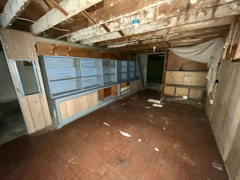 Basement office at 5900 Winthrope Avenue with panel walls, exposed ceiling beams, and built-in shelving.