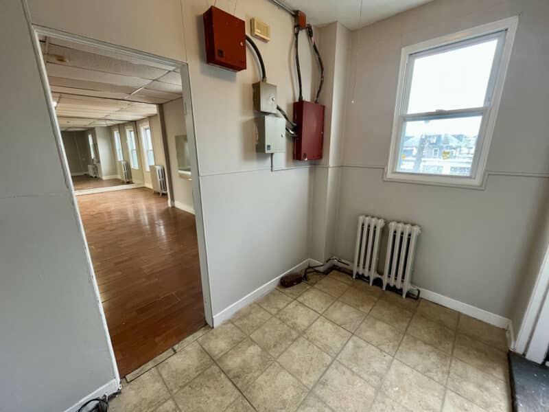 Rear second-floor room at 5839 Belair Road with tiled floor, utility panels, and radiator.