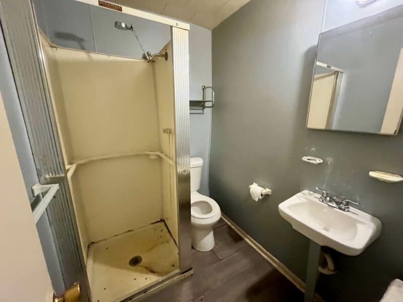 Bathroom in Apartment 1 at 4831 Belair Road with standing shower, toilet, and wall-mounted sink.