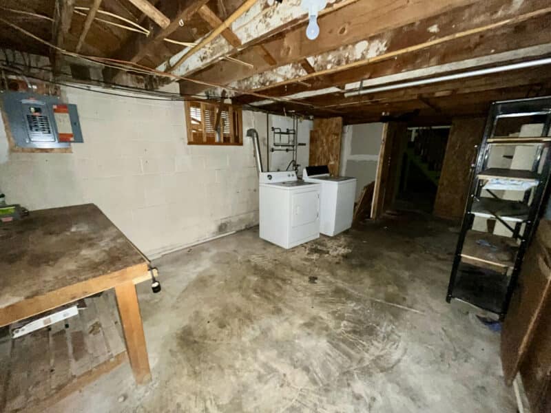 Laundry and utility room in basement of 5900 Winthrope Avenue with utility sink, appliances, exposed ceiling, and concrete floor.