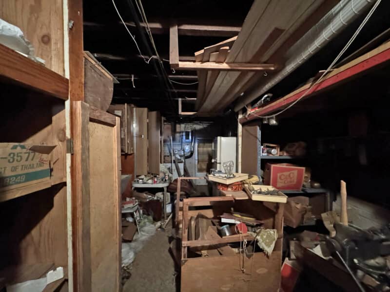 Unfinished basement section at 3412 Esther Place featuring exposed beams, utility lines, and built-in workbenches with storage.