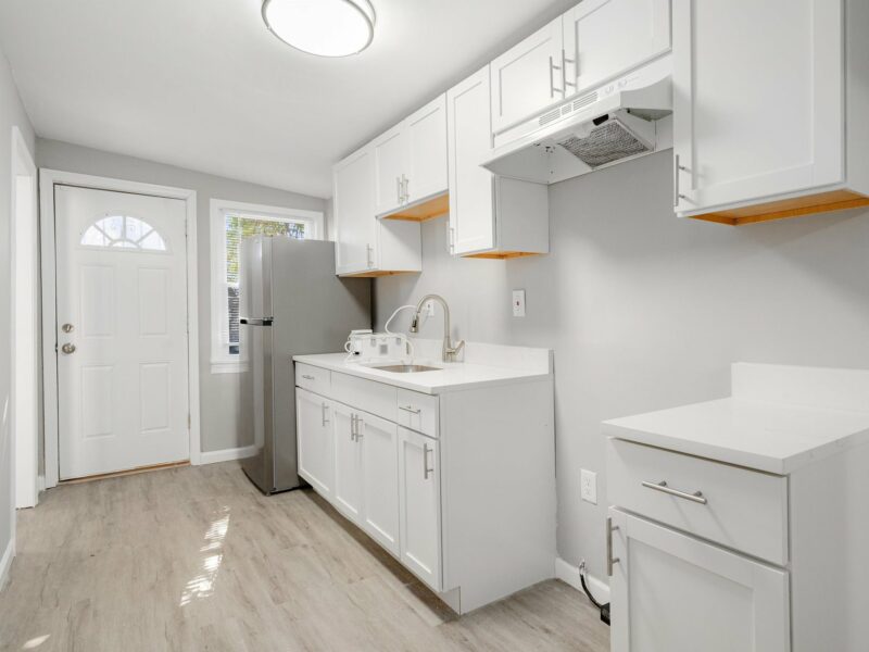 Kitchen at 5248 Cordelia Avenue with white cabinets, stainless steel sink, and rear entry door.