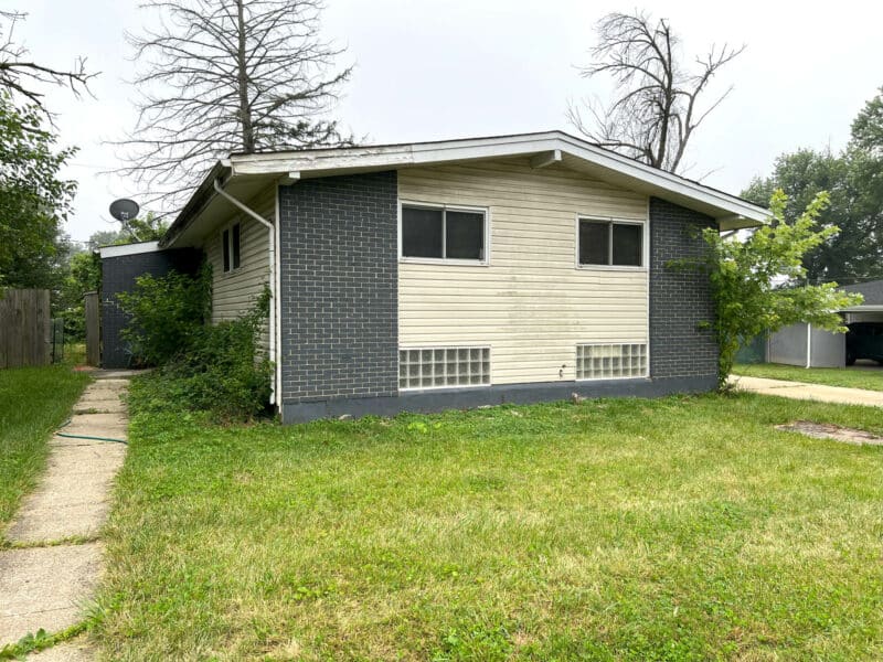 Front exterior of split-level home with partial brick facade, grassy lawn, and concrete walkway in Baltimore County.