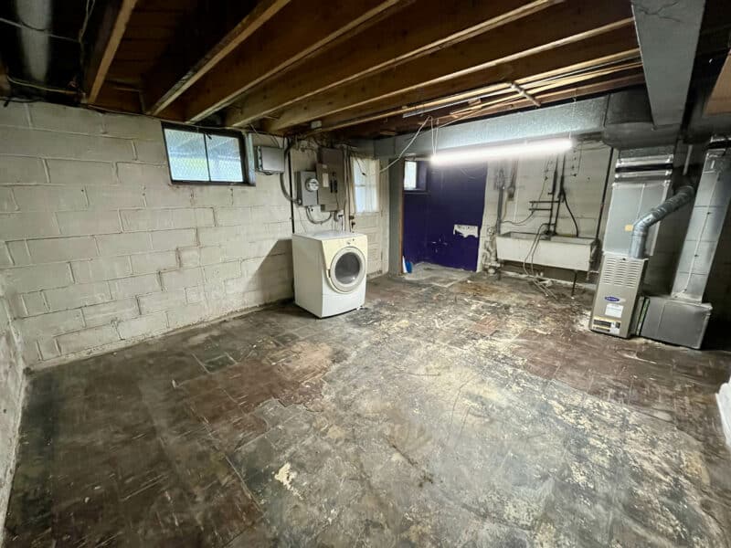 Basement with washer, dryer, exposed ceiling joists, HVAC system, and unfinished concrete block walls.