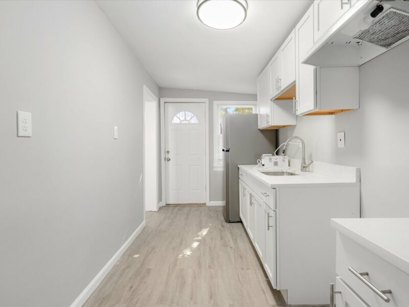 Kitchen at 5248 Cordelia Avenue with white cabinets, stainless steel sink, and rear entry door.