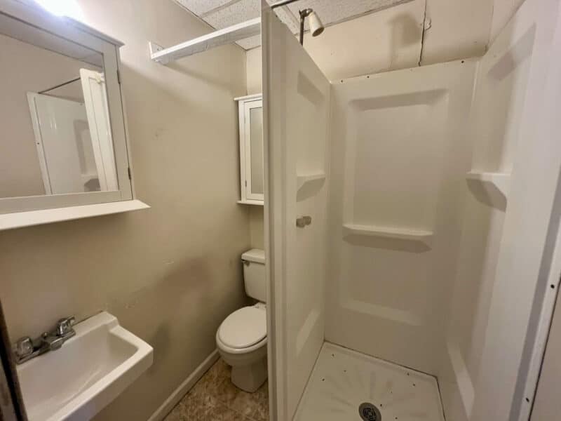 Bathroom in Apartment 2 at 4831 Belair Road featuring stand-up shower, toilet, and wall-mounted sink.