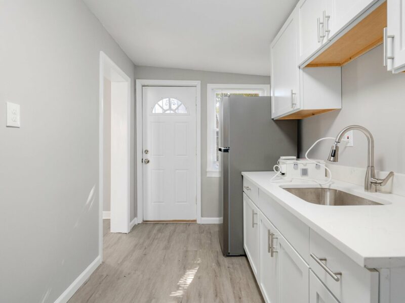 Kitchen at 5248 Cordelia Avenue with white cabinets, stainless steel sink, and rear entry door.