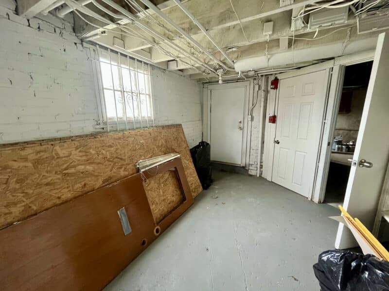 Second basement room with exposed ceiling, storage doors, and painted concrete floor at 5839 Belair Road.