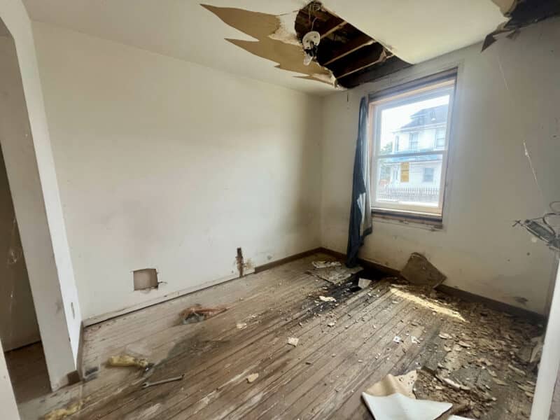 Interior room with hardwood floors, peeling ceiling, and wall openings