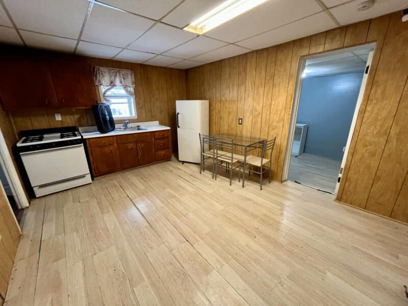 Kitchen area in Apartment 3 at 4831 Belair Road with wood panel walls, gas stove, refrigerator, and dining space