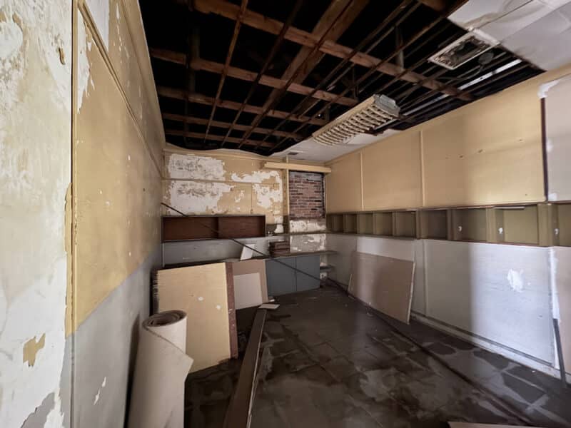 Vacant storage or utility room with partial ceiling removal and scattered construction materials.
