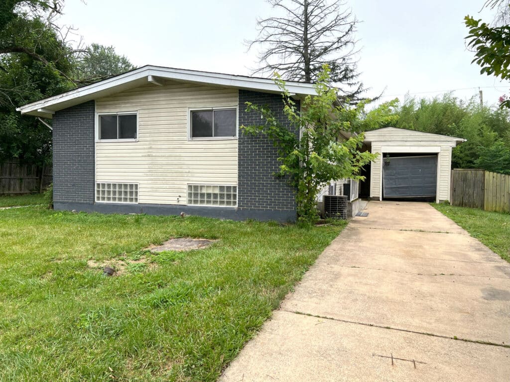 Split-level brick and vinyl home with front yard and driveway leading to attached garage at 4761 Bonnie Brae Road, Pikesville.