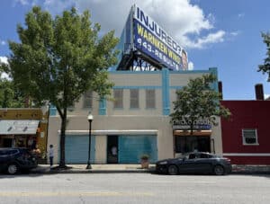 Street view of commercial building at 5109 Park Heights Avenue with billboard, retail storefronts, and visible tenant signage in Northwest Baltimore.