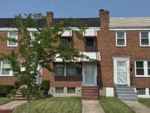 Front view of a brick townhome at 4020 Dudley Avenue in Baltimore’s Belair-Edison neighborhood, with covered entry, manicured lawn, and traditional awning.