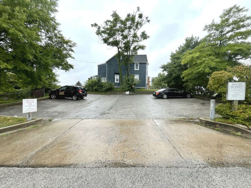 Rear parking lot at 4921 Harford Road with asphalt surface and surrounding trees.