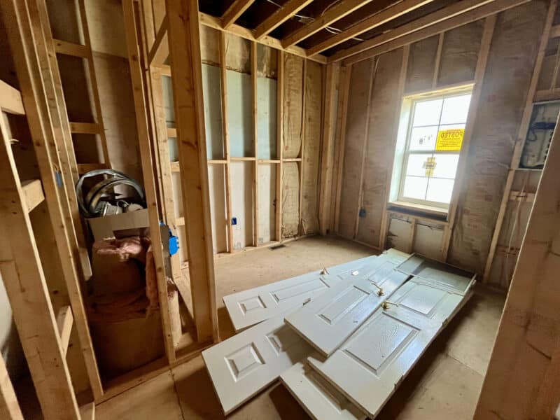 Room under renovation with exposed framing and stacked panel doors