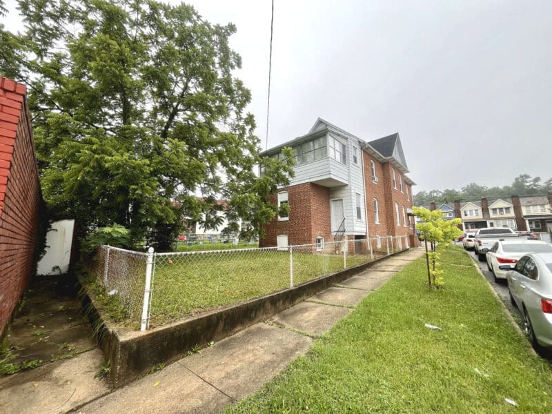 Fenced rear yard and side view of 5839 Belair Road with sidewalk and grassy area.