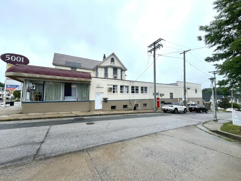 Side view of the mixed-use building at 5001 Harford Road with storefront windows and upper-level residential facade.