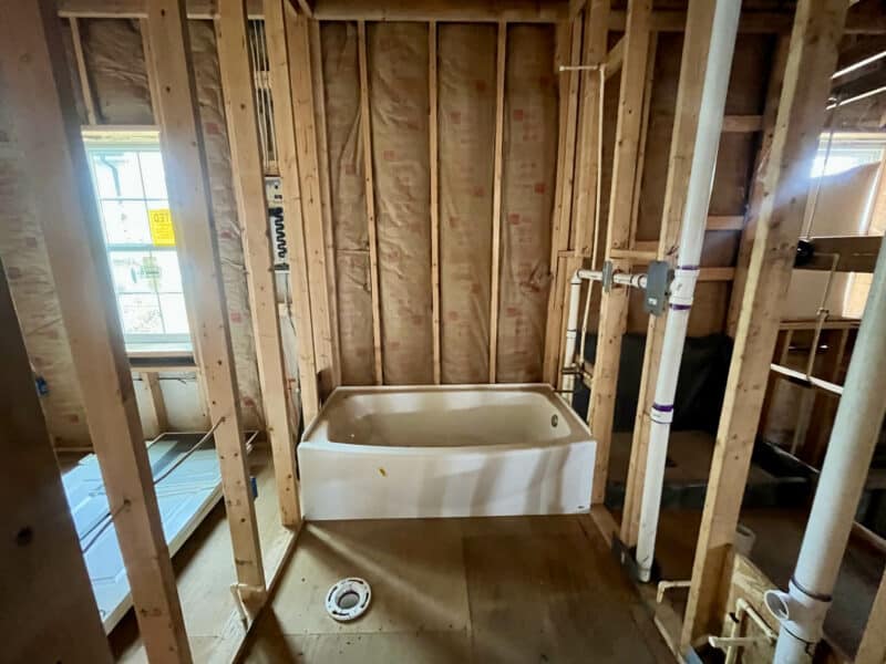 Partially constructed bathroom with tub installed and exposed framing