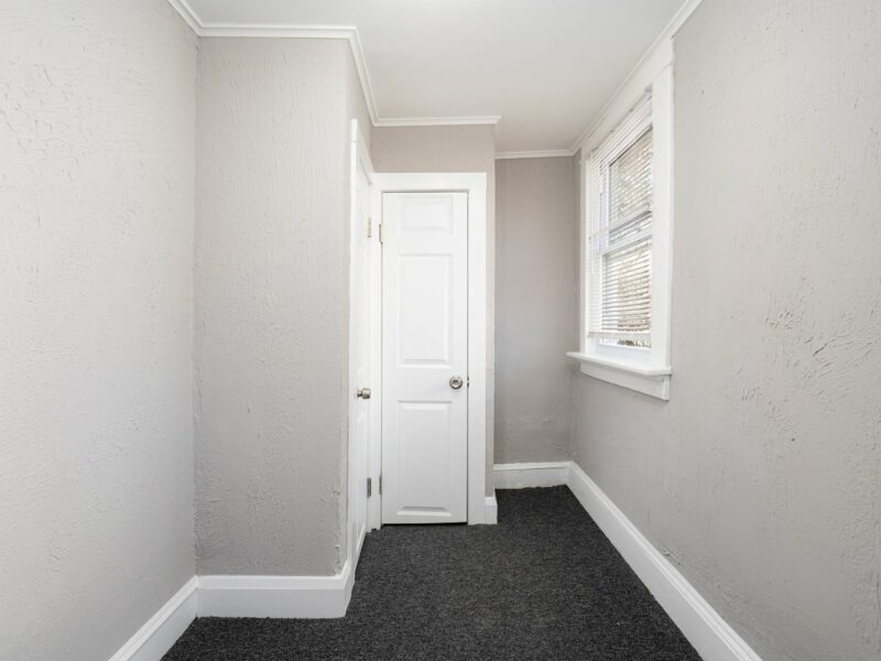 Narrow bonus room with carpeted flooring, two windows, and a small closet in an updated Baltimore bungalow.