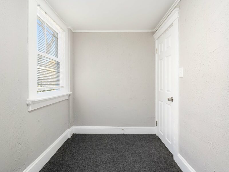 Bonus room with two windows and closet door, featuring neutral walls and carpet flooring in a renovated Baltimore bungalow.