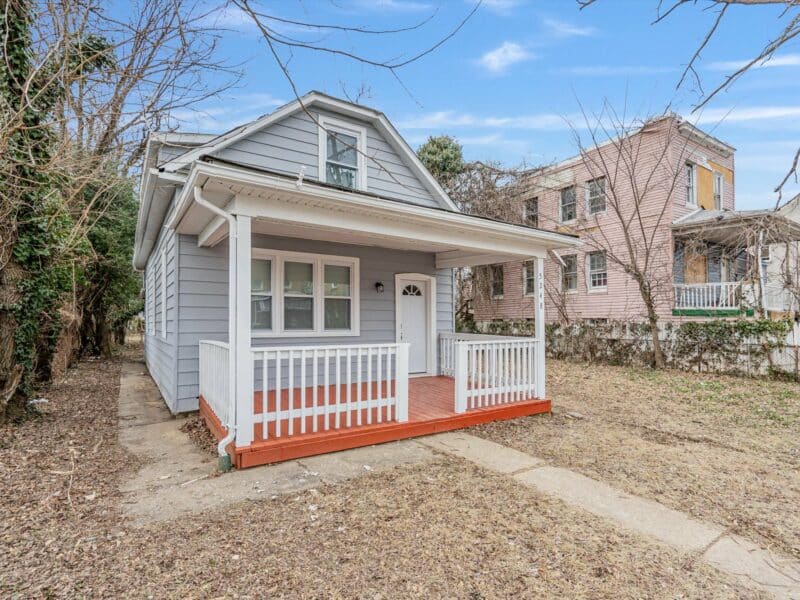 Front-right angle view of 5248 Cordelia Avenue, showing renovated bungalow with white-trimmed porch and vinyl siding.