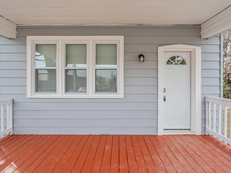 Close-up view of the front porch at 5248 Cordelia Avenue with red-painted decking, white railing, and front entry door.