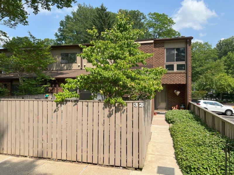 Front two story brick townhouse condo unit with fenced grassy yard.