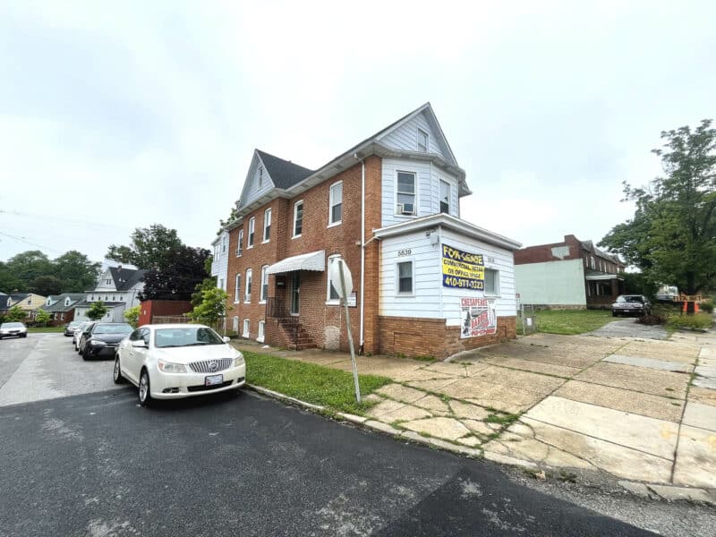 Street-level view of 5839 Belair Road with brick commercial building, front entry steps, and surrounding block.
