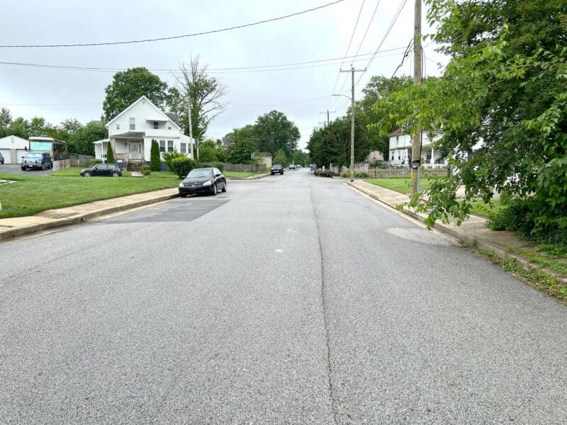 Street view of Winthrope Avenue in Baltimore’s Hamilton neighborhood, showing single-family homes, parked cars, and overhead utility lines.