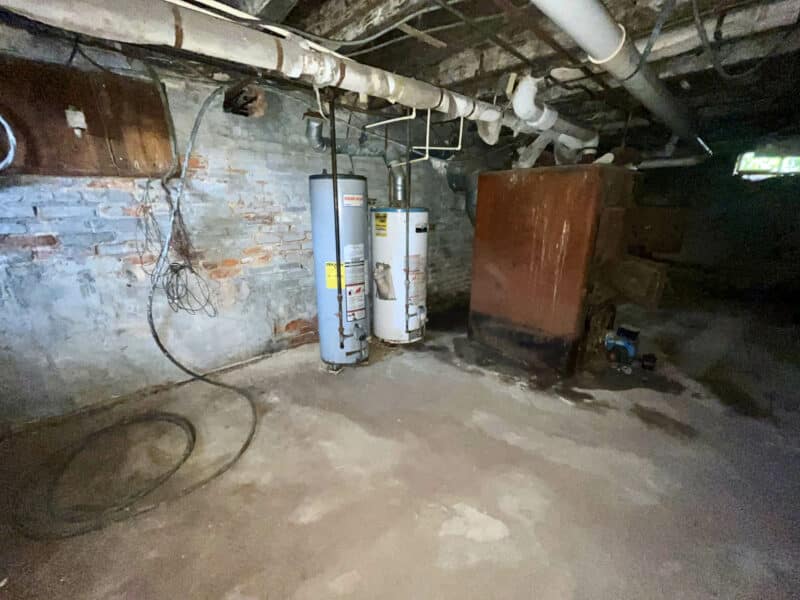 Basement area with exposed brick, two water heaters, and furnace system