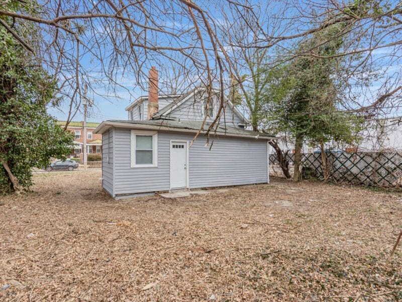 Rear and side view of 5248 Cordelia Avenue with vinyl siding, rear entry door, and open yard.