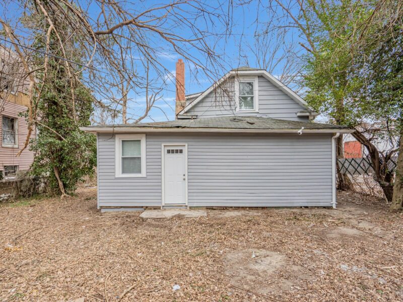 Rear exterior of 5248 Cordelia Avenue featuring gray vinyl siding, rear door, and open backyard.