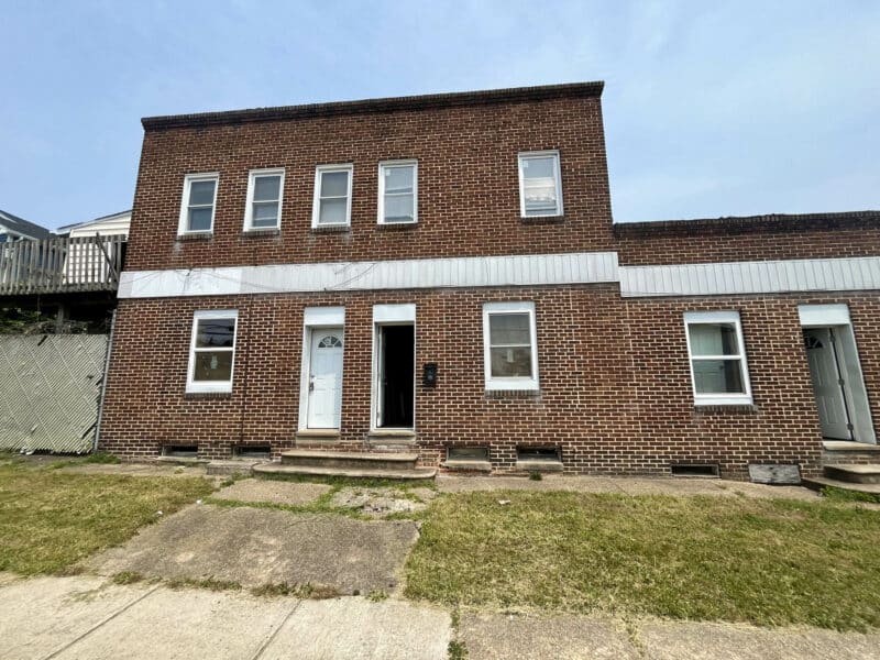 Two-story brick apartment building with multiple entrances and a fenced side yard