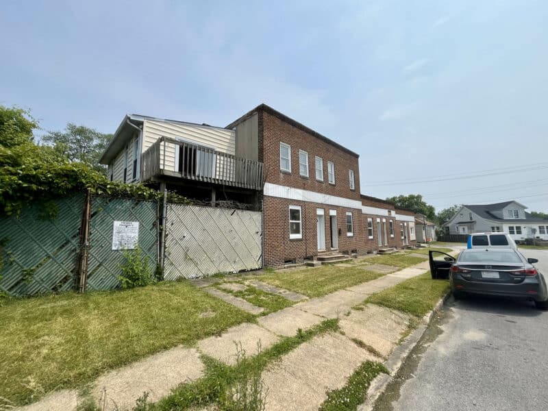Side angle of 539-549 45th Street showing multi-entry brick facade and fenced yard with upper-level deck in Dundalk’s Harbor View neighborhood.