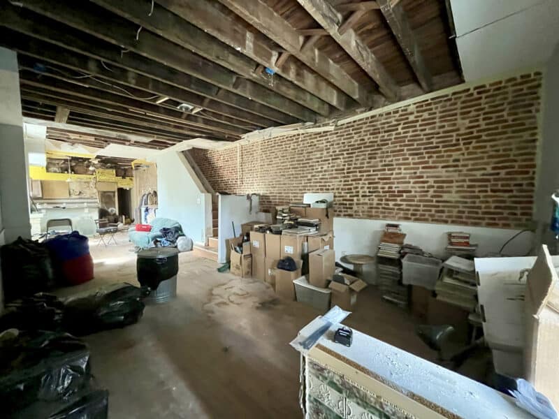 Interior view of the living room at 2307 E. Preston Street showing exposed joists, brick walls, and renovation debris.
