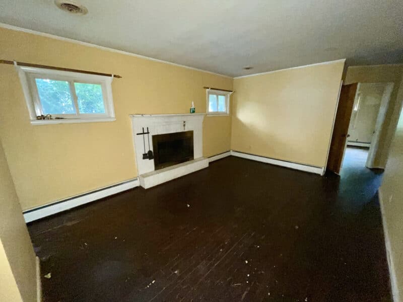Living room of 5900 Winthrope Avenue with wood flooring, brick fireplace, and yellow walls.