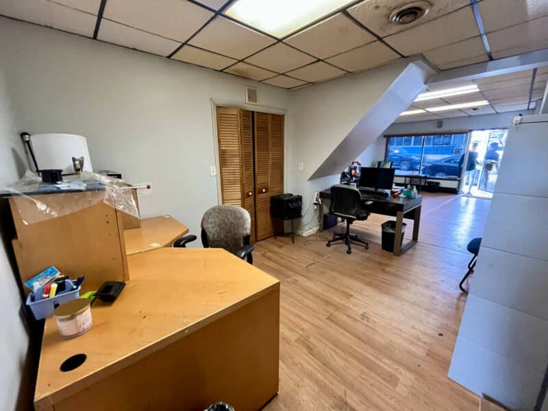 Office interior with desks, chairs, and street-facing window inside a Tag & Title business at 4831 Belair Road.
