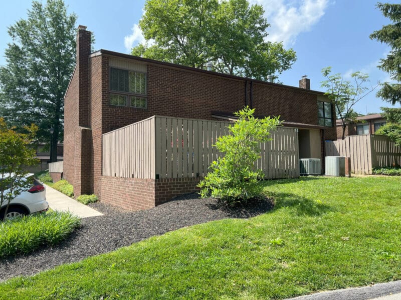 Back yard view of two story brick townhouse condo unit with fenced yard.