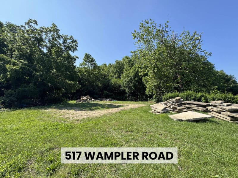 Grassy clearing with stacked timber and tree-lined perimeter on the 11.84 ± acre Wampler Road residential development site in Middle River, Maryland.