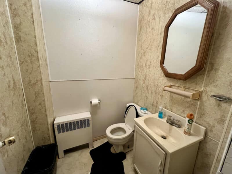 Bathroom with toilet, sink, and mirror inside Tag & Title unit at 4831 Belair Road.