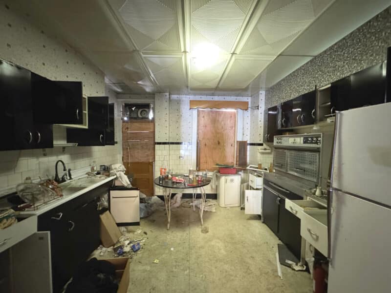 Kitchen of 3412 Esther Place featuring retro appliances, black cabinetry, and cluttered surfaces, offering a prime opportunity for renovation and modernization.