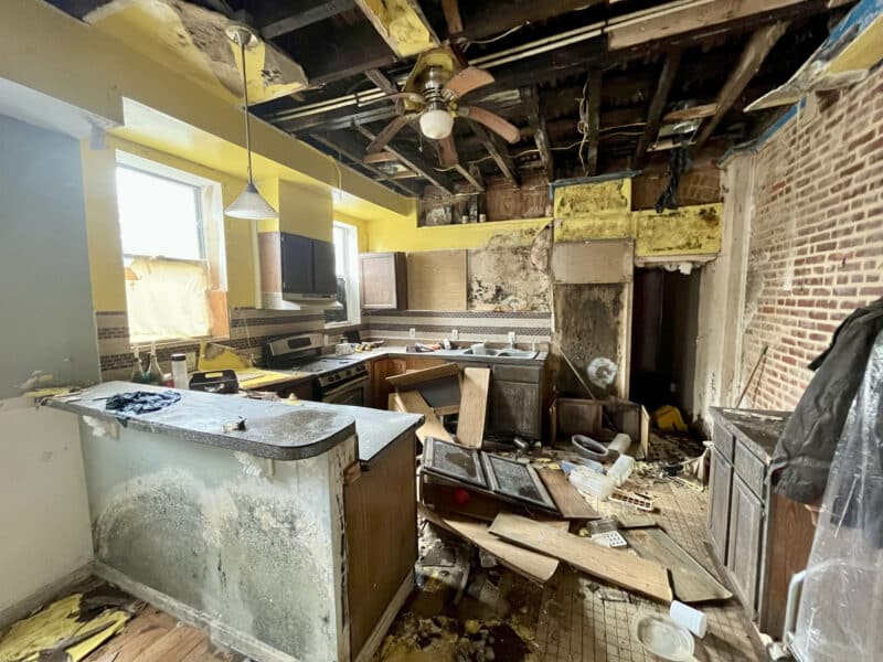 Kitchen at 2307 E. Preston Street in need of full renovation, with damaged cabinetry and exposed ceiling joists.
